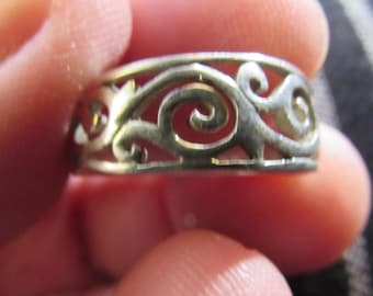 May include: Silver ring with a delicate, intricate design of swirling lines and curves.