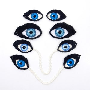 May include: A set of seven crocheted blue eyes with black pupils, connected by a white crocheted chain.