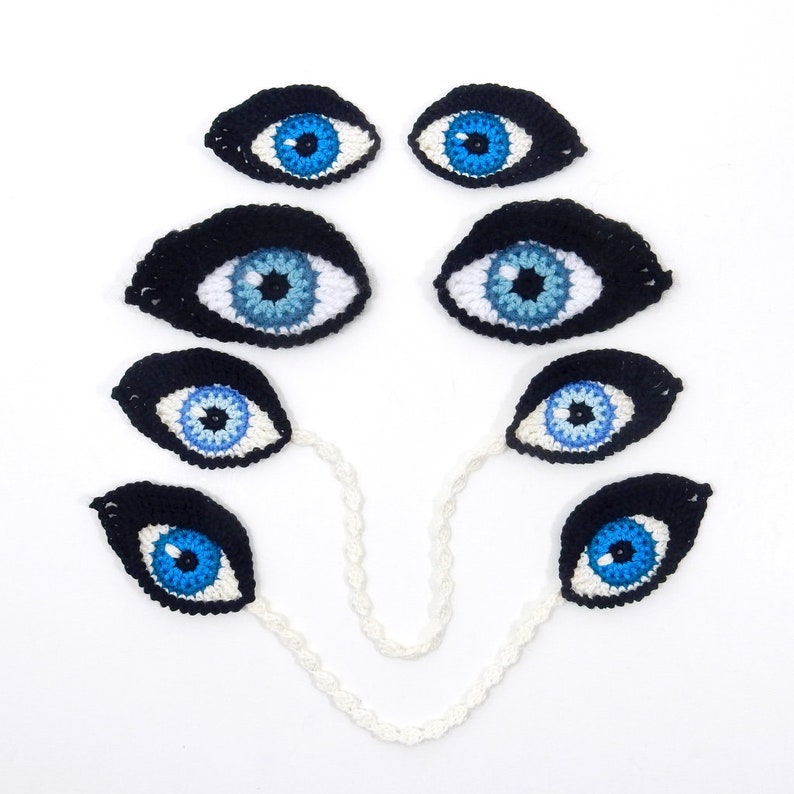 May include: A set of seven crocheted blue eyes with black pupils, connected by a white crocheted chain.
