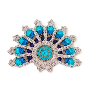 May include: A crocheted mandala with a circular design in shades of brown, blue, and teal. The mandala has a scalloped edge and is made with a variety of stitches.