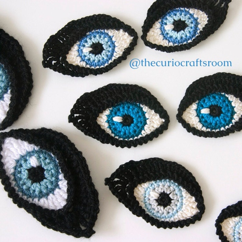 May include: A set of seven crocheted eyes in various sizes. The eyes are made with black, white, blue, and light blue yarn. The eyes are all oval shaped and have a black pupil in the center. The eyes are perfect for adding a whimsical touch to any craft project.