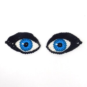 May include: Two crocheted eyes with black eyelashes, white irises, and blue pupils.