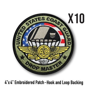 May include: A set of 10 embroidered patches featuring the United States Coast Guard Drop Master insignia. The patch is green, black, and gold with a red, white, and blue American flag. The patch is 10 cm by 10 cm and has hook and loop backing.