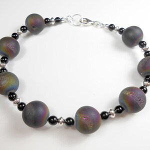 May include: A bracelet featuring iridescent black agate beads with silver accents.