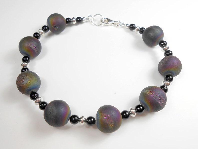 May include: A bracelet featuring iridescent black agate beads with silver accents.