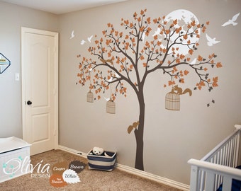 May include: A wall decal featuring a brown tree with orange leaves, a white moon, and birds. There are also two cages with squirrels hanging from the branches. The decal is perfect for a nursery or child's room.