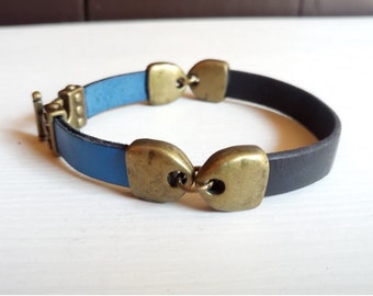 May include: A blue and black leather bracelet with brass accents. The bracelet has a clasp closure.