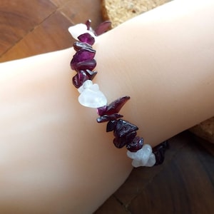 Può includere: Un braccialetto fatto di pietre preziose viola e bianche. Il braccialetto è fatto di pietre naturali ed è un bellissimo gioiello.