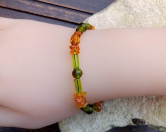 Könnte beinhalten: Ein Armband aus Bernstein- und grünen Glasperlen. Das Armband befindet sich an einem Handgelenk.