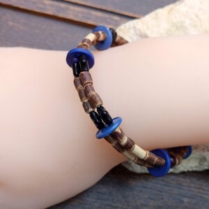 May include: A double-strand bracelet made with brown and white wooden beads and blue round buttons.