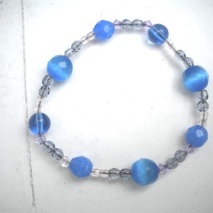 Puede incluir: Un brazalete de cuentas azules y transparentes con cuentas facetadas de color azul claro y cuentas transparentes.