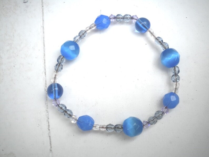 Puede incluir: Un brazalete de cuentas azules y transparentes con cuentas facetadas de color azul claro y cuentas transparentes.