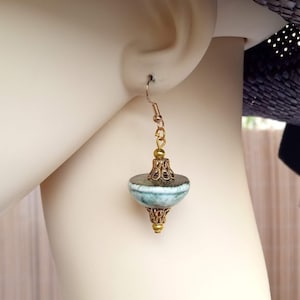 May include: A pair of dangle earrings with a blue and green ceramic bead and gold accents.