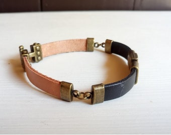 May include: A brown and black leather bracelet with a brass clasp and decorative accents.