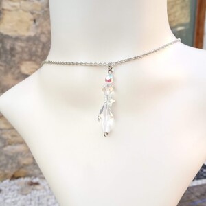 May include: A silver chain necklace with a clear crystal pendant. The pendant is made of faceted crystal and hangs from the chain.
