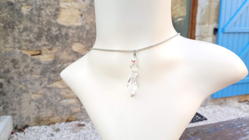 May include: A silver chain necklace with a clear crystal pendant shaped like a leaf.