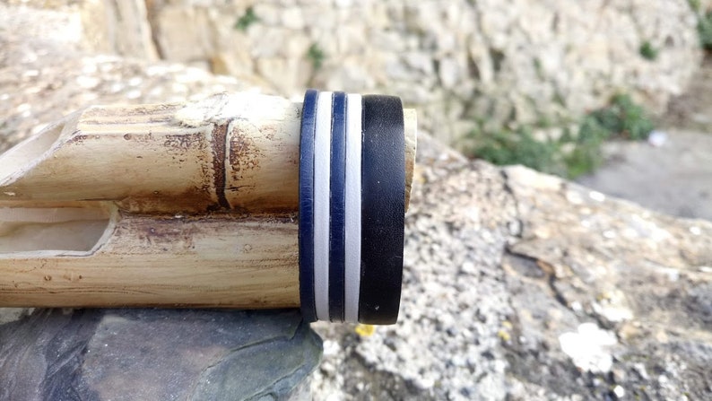 May include: Close-up of a bamboo flute with a black and white striped band around the end.
