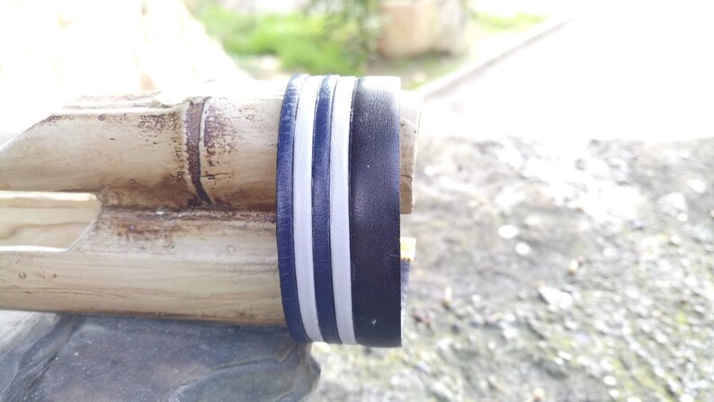 May include: Close-up of a wooden object with a black and white striped band around it. The band is made of two white stripes and a black stripe.