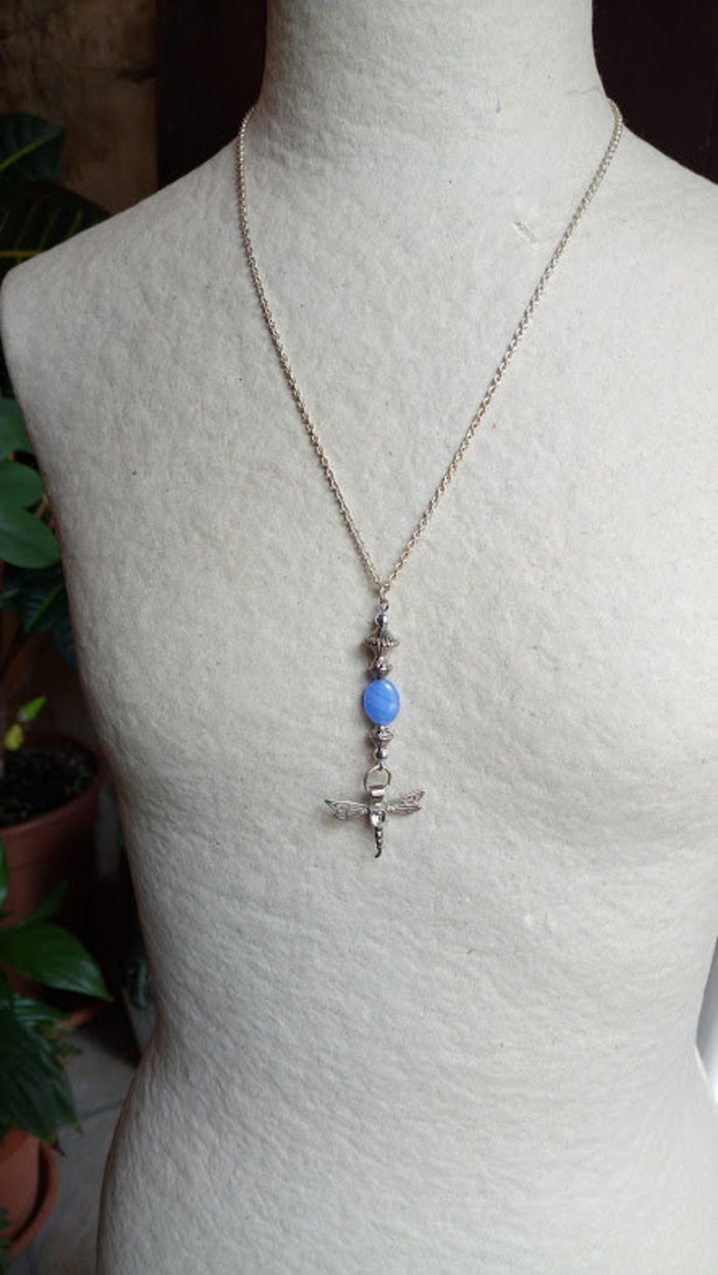 Puede incluir: Un collar de cadena de plata con una piedra ovalada azul y un colgante de lib&eacute;lula.