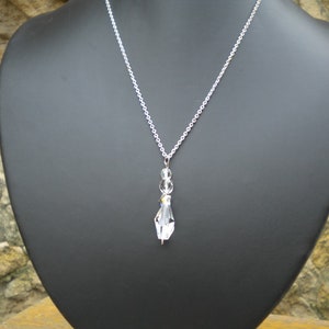 May include: A silver chain necklace with a clear crystal pendant. The pendant is made up of several small crystals.