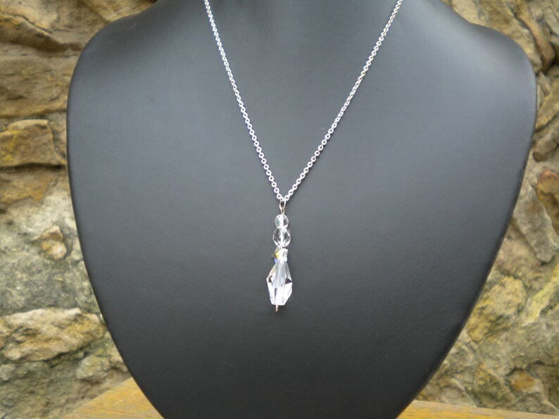 May include: A silver chain necklace with a clear crystal pendant. The pendant is made up of several small crystals.