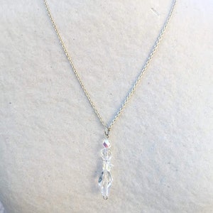 May include: A silver chain necklace with a clear crystal pendant. The pendant is made of faceted crystals that are arranged in a teardrop shape.