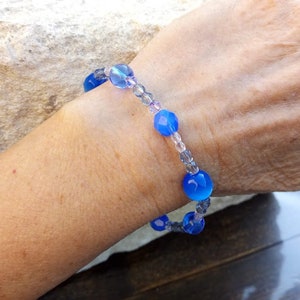 Puede incluir: Un brazalete de cuentas de vidrio azul y transparente con una banda el&aacute;stica.