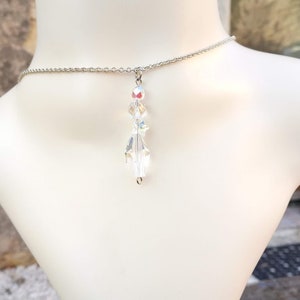 May include: A silver chain necklace with a clear crystal pendant. The pendant is made of faceted crystals that reflect light.