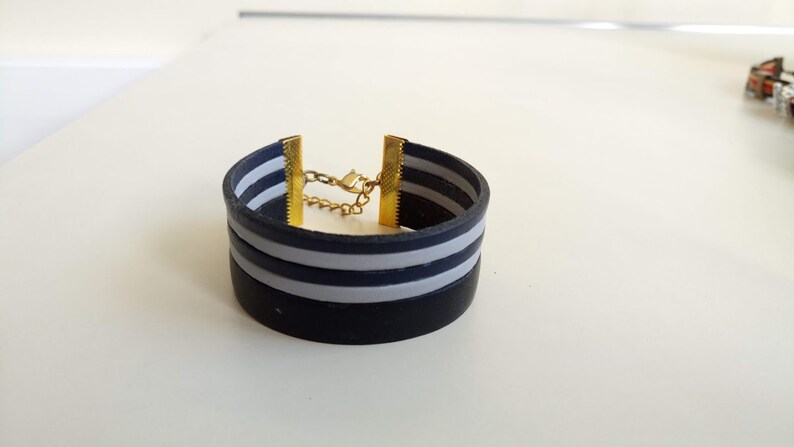 May include: A black and white striped silicone bracelet with a gold chain and clasp.
