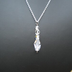 May include: A silver chain necklace with a clear crystal pendant. The pendant is made up of several faceted crystals, including a star-shaped crystal.