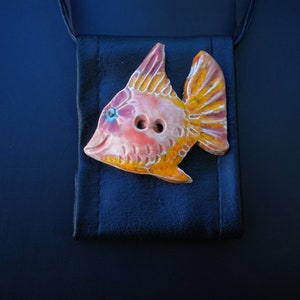Pu&ograve; includere: Un bottone di ceramica a forma di pesce con smalto arancione, rosa e giallo. Il bottone ha due bottoni neri per gli occhi.