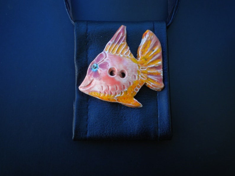Pu&ograve; includere: Un bottone di ceramica a forma di pesce con smalto arancione, rosa e giallo. Il bottone ha due bottoni neri per gli occhi.