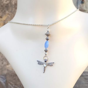 Puede incluir: Un collar de cadena de plata con un colgante de lib&eacute;lula y cuentas de vidrio azul.