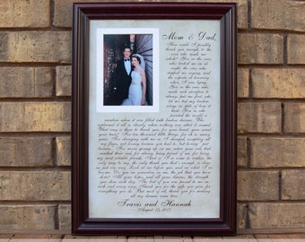 May include: A framed wedding photo with a handwritten letter to the bride and groom's parents. The frame is cherry wood with a white mat. The background is A3 paper and the font is black. The text in the letter reads "Mom & Dad, Thank you so much for the incredible support you have provided us throughout our lives. What we may not always thank you for, but what we will always treasure is the sheer amount of love and support you have given us.  We have learned so much from you and we are so grateful for everything you do. All our love, Travis and Hannah, August 18, 2012."