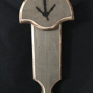 May include: A wooden wall mount with a gray finish and a black bird footprint design. The mount has a decorative top and a long, narrow body.