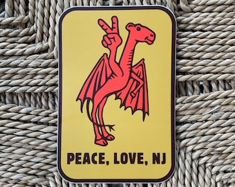 May include: A yellow sticker with a red and black cartoon creature with wings and a peace sign. The text on the sticker reads "Peace, Love, NJ".