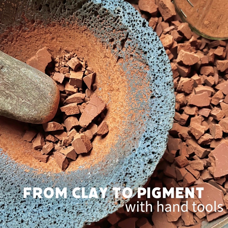 Puede incluir: Primer plano de un mortero y una maja que se utilizan para moler arcilla roja en pigmento. El texto "FROM CLAY TO PIGMENT with hand tools" es visible en la parte inferior de la imagen.