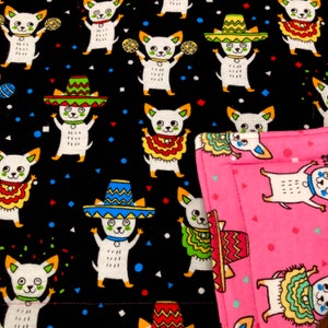 May include: A black and pink fabric with a repeating pattern of white dogs wearing sombreros and playing maracas. The dogs are surrounded by colorful confetti.