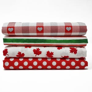 May include: Four folded fabric rolls stacked on a white background. The top roll has a red and white plaid pattern with heart accents. The second roll has green and red stripes. The third roll has red maple leaves on white. The bottom roll has white polka dots on red.