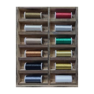 May include: A wooden display rack with two vertical columns containing twelve spools of metallic thread in various colours including gold, red, silver, green, bronze, black, and white, arranged neatly on horizontal shelves for organised storage.