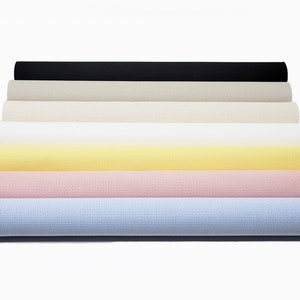 May include: A set of eight rolled-up fabric swatches in various colors, including black, beige, white, yellow, pink, and light blue. The fabric has a textured, woven appearance.