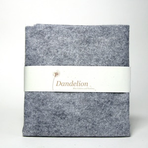 May include: A grey felt fabric swatch with the text "Dandelion Fine Felts and Fabrics" printed on a white label.