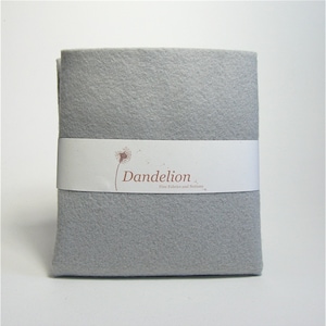 May include: A sheet of grey felt fabric with a white label that reads "Dandelion Fine Fabrics and Notions".