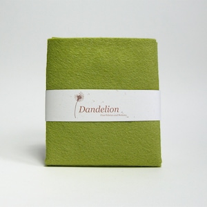 May include: A folded piece of green felt fabric with a white label that says "Dandelion Fine Fabrics and Notions".
