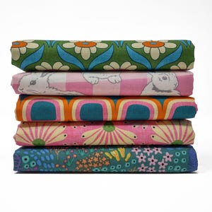 May include: Five folded fabric pieces with diverse patterns are stacked. The top fabric has a green background with white and orange daisy-like flowers. Other fabrics feature bunnies, retro arches, and floral designs.