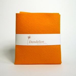 Peut inclure: Une feuille de feutre orange vif avec une étiquette blanche qui indique "Dandelion Fine Fabrics and Notions".