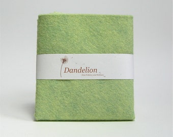May include: A light green felt fabric swatch with the text "Dandelion Fine Fabrics and Notions" on a white label.