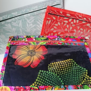 May include: Three zippered pouches in different patterns. One is pale blue with a leaf design, another is red with a leaf pattern, and the third is a vibrant mix of colours with a large floral design and a clear window.