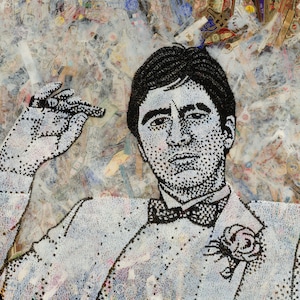 Op de afbeelding: Een zwart-wit portret van een man in een wit pak met een strikdas en een bloem op zijn revers. De afbeelding is gemaakt van kleine, afzonderlijke stukjes materiaal, waardoor een textuur-effect ontstaat.