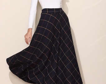 May include: A woman wearing a white long-sleeved shirt and a black and white plaid skirt. The skirt is knee-length and has a flared silhouette.
